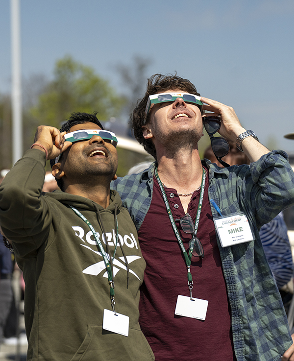 Two students use special glasses to look at the 2024 solar eclipse.